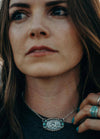 girl wearing oval necklace with cattle brand 